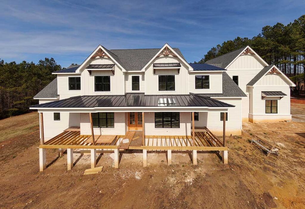 A construction crew framing the wooden skeleton of a single-family house under a clear sky.